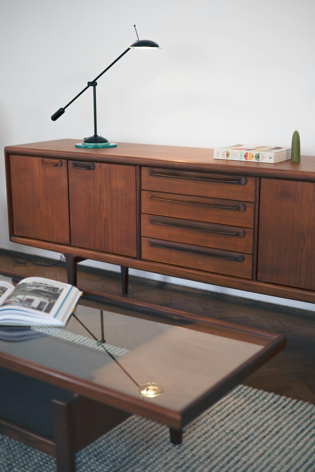 Wooden sideboard with lamp and books in a modern living room.