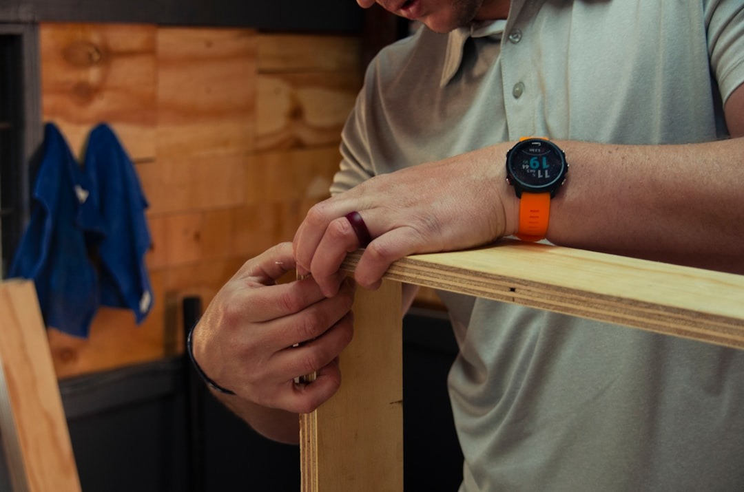 Person assembling wooden panels in a workshop.